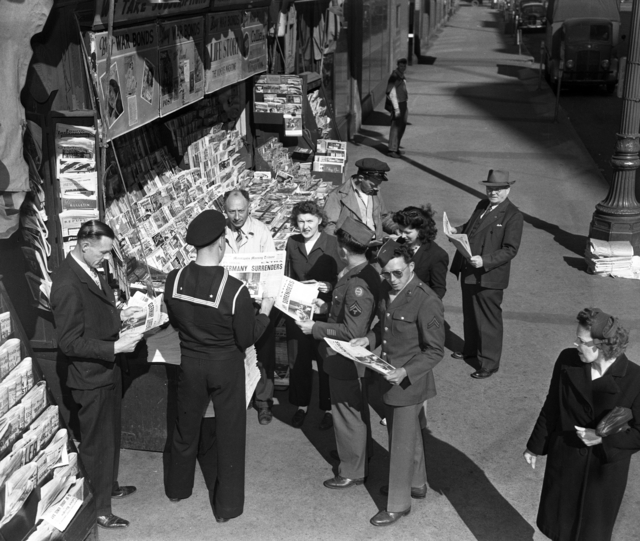 People reading about Germany's surrender at the end of WWII