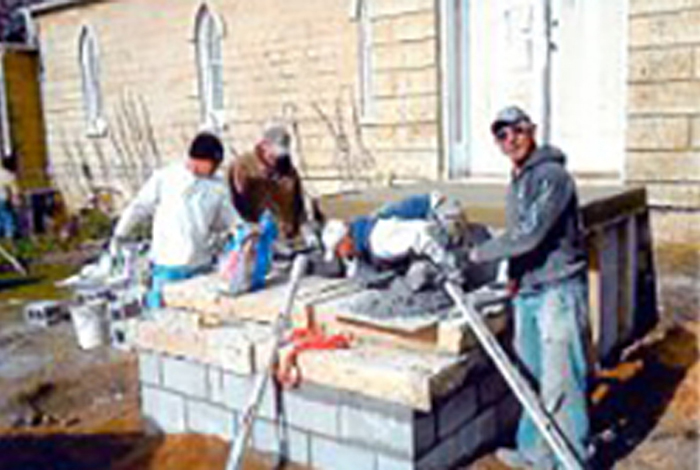 Four workers are building some kind of outdoor structure.