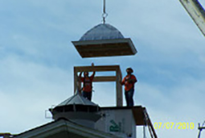 An arch is being move into place with two people signaling.