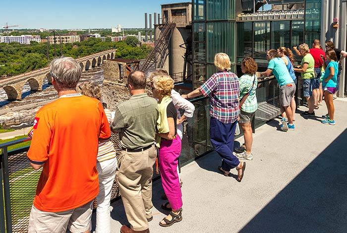 People standing on the observation deck looking at the river and cityscape.