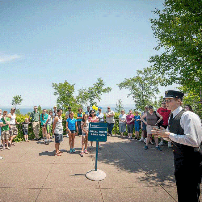 Tour guide dressed in lighthouse keeper uniform addressing a large group