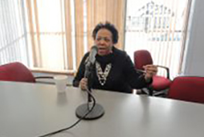A seated woman is speaking in front of a microphone.