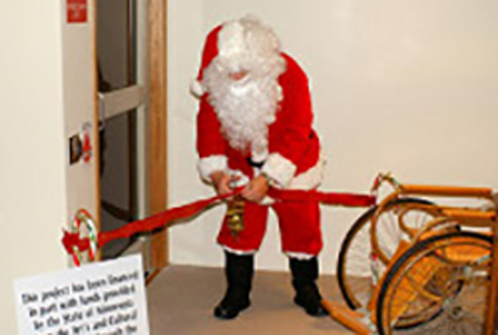 Santa is cutting a ribbon.