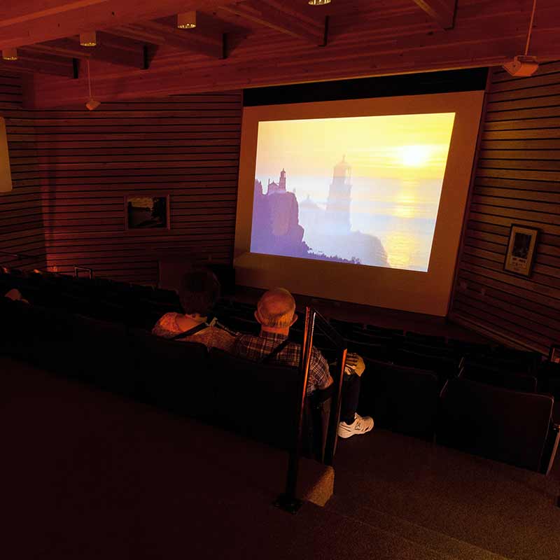 A couple sitting in a small theater watching a film projected onto a screen