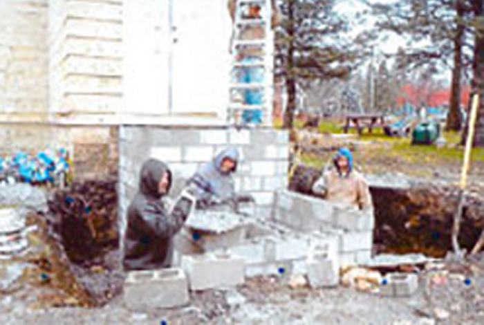 Three workers are building a wall.