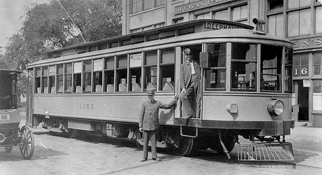 Photo of a streetcar during its layover, two conductors stand with it, Minneapolis, 1905.