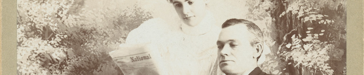 Thomas J. and Mary Meighen look at a newspaper. Photo date: 1899.