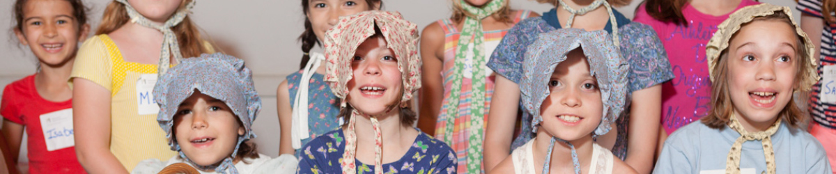 Young girls in bonnets smiling and laughing.