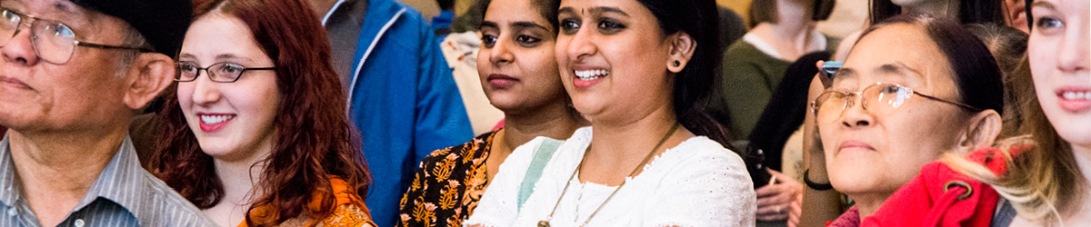 A group of smiling people stand facing a common focal point.