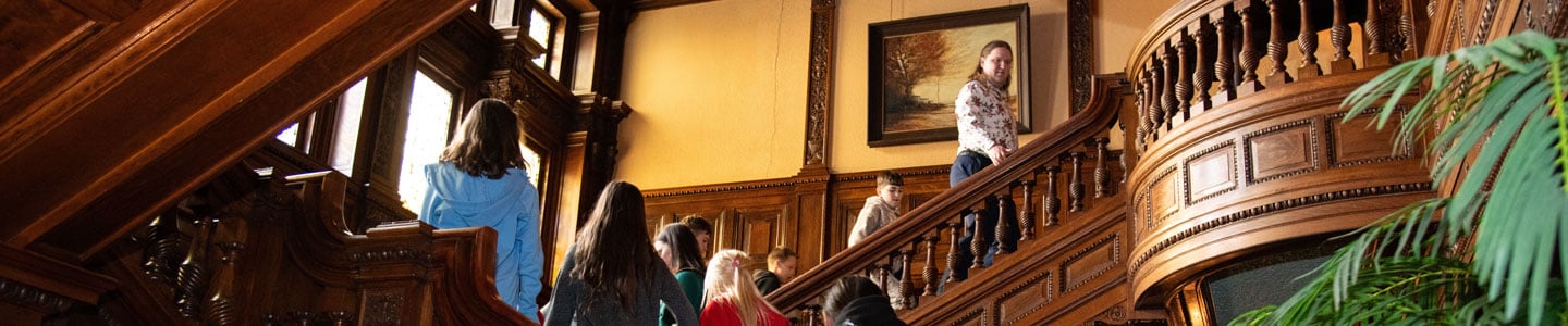 Image of students following a tour guide up the stairs at James J. Hill House. Image of students following a tour guide up the stairs at James J. Hill House.
