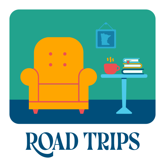 Road trips. A sofa sits next to a table with a mug and stack of books.