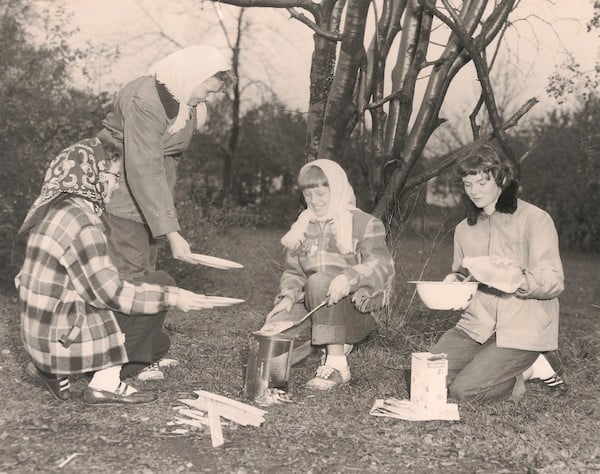 Four Girl Scouts cookkng over a campfire
