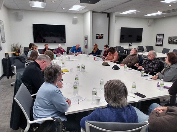 A large group of 19+ people sitting around a conferernce table
