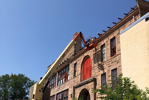 Exterior of the Sandstone school with Telescopic Boom Lift with worker repairing roof edge
