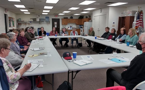 A group of 18+ people meeting round set up tables