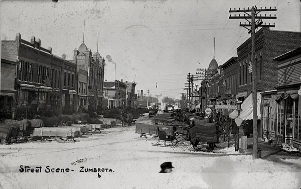 Several dozen sleighs parked on the street in front of stores. On photo is written Street scenc - Zumbrota. ca. 1900
