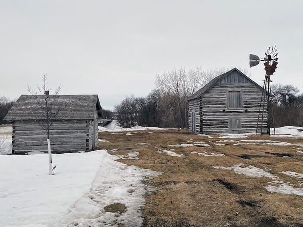 Two log building and a windmill in the Sand Hill Settlement
