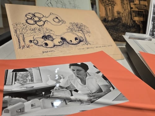 Close of of display case showing and illustation and a photo of woman working on building model