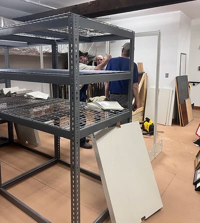 Archival shelves being assembled by three men