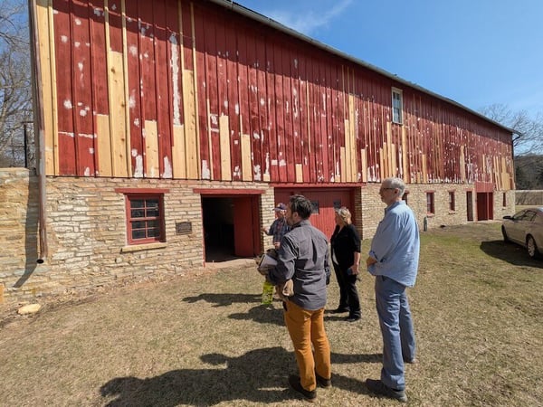 People standing looking at a red barn