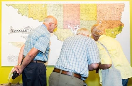 Three old men looking over a map on the wall