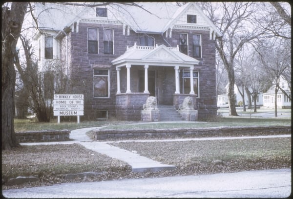Large stately stone house with sign in front saying, The Hinkley House Home of the Rock County Historical Society Museum