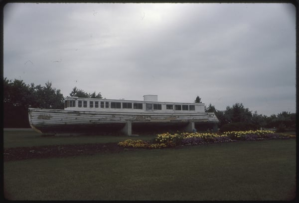 Side image of the boat Golden Bantum on land held aloft by concrete supports, Ortonville, MN-Sept. 1985