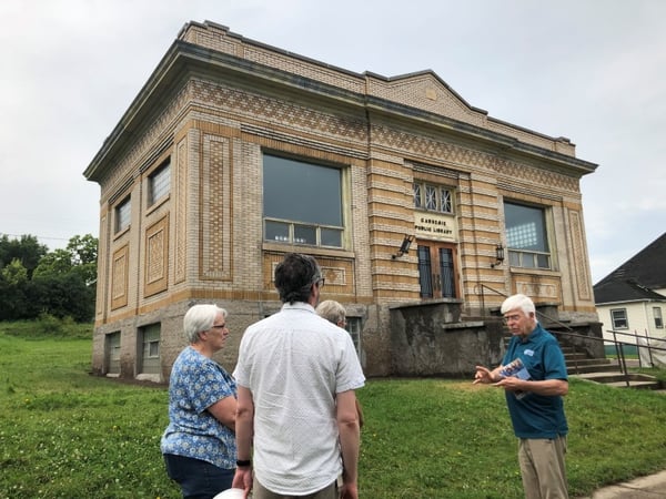 Three people standing outside of the Browns Valley Carnegie Public Library talking on the sidewalk