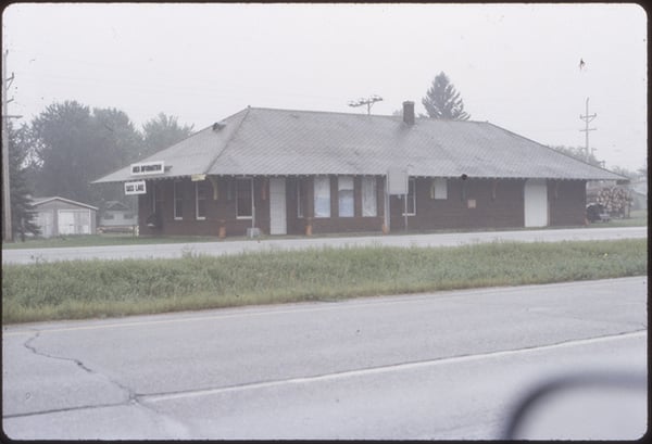 Exterior of the Logging Museum, Cass Lake, MN photo taken from a car. Drivers mirror is visable