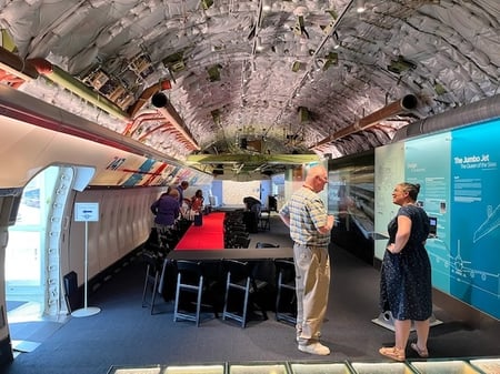 Fuselage of airliner converted to museum gallery with people standing and talking