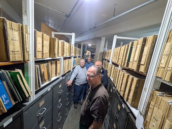Four people standing between archival shelves and filing cabinets at the Minnesota Transportation Museum