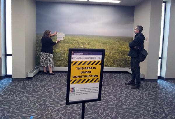 Photo of two people at the lincoln exhibit area, with one person looking on as another is showing plan