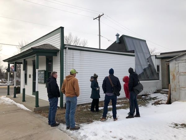 Six people standing outside of the Gust Akerlund Studio inspecting the exterior