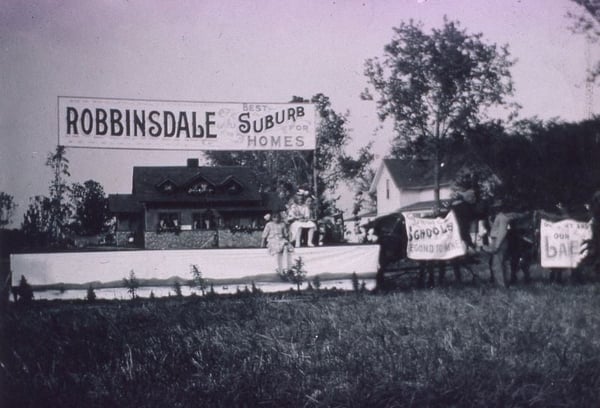 Robbinsdale float with sign saying Best Suburb for Homes. Two girls sit on the float
