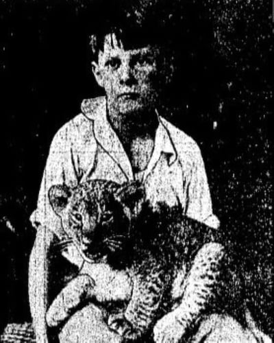 Boy holding lion cub on lap