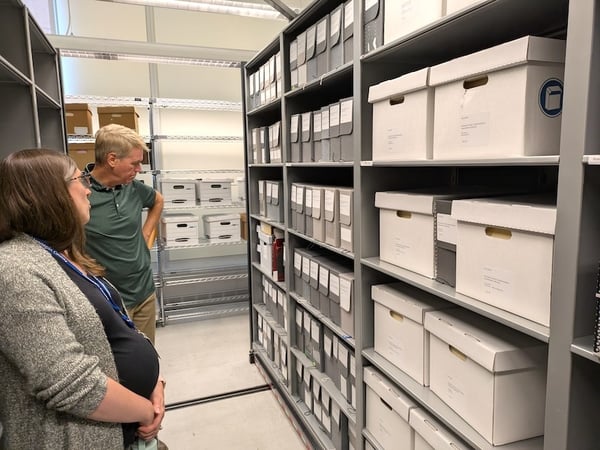 Two people looking over boxes on archival shelving