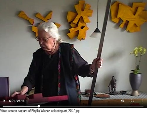 Video screen capture of Phyllis Wiener, selecting art, 2007 with text