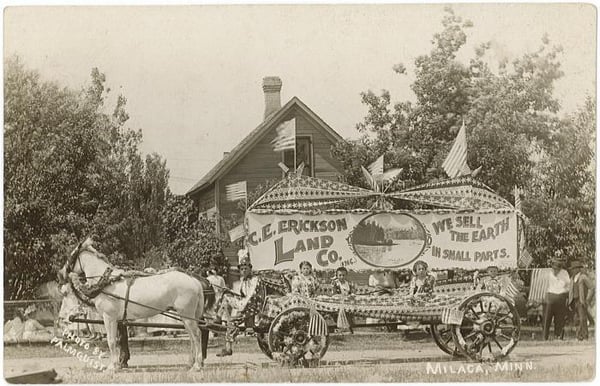 Vintage postcard showing a horse drawn parade float for the C.E. Erickson Land Co. on a residential street