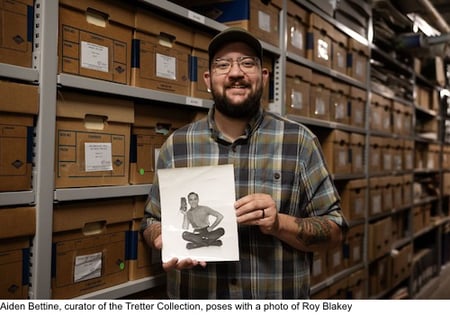 Aiden Bettine, curator of the Tretter Collection, poses with a photo of Roy Blakey
