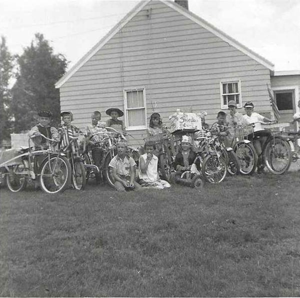 Black and white photograph snapshot of children dressed in costume and have bicycles or bikes with them. 1956