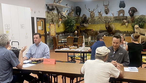 People in at tables talking to one another. In background are stuffed animals.png