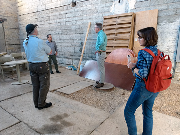 Four people talking in the Mill City Museum courtyard. Limestone walls of the museum are around them.