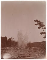 An explosion in a log-choked river throws up water and wood into the air.