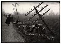 People in white collars, hats, and long coats walk along a road at right, with burned cars and leaning power lines at right.