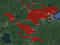 Splotches of red indicate the reach of foreset fires on top of a green background, with bodies of water visible in shades of blue, green, and indigo.