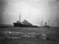 A wave meets a sandy shore, while behind it a ship moves through choppy waves.
