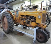 Tricycle-tired tractor with clam shell fenders parked inside a building.