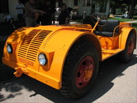 A four-wheeled orange jeep parked outside a building.