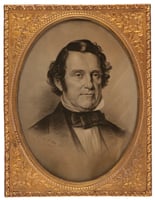 Gold frame with an oval black-and-white image of a man's head and shoulders. He wears a suit jacket with a bow tie and a high shirt collar.