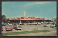 1950s-style cars sit in a parking lot in front of a single-story building with the words "Red Wing Potteries Salesroom" painted on the front facade.